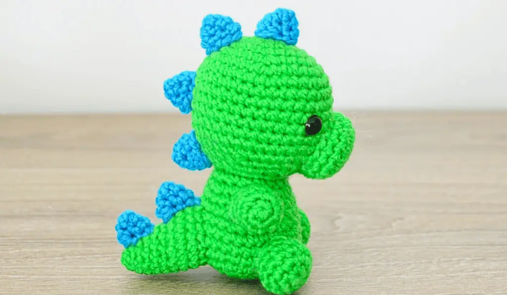 A green crochet dinosaur with blue spikes