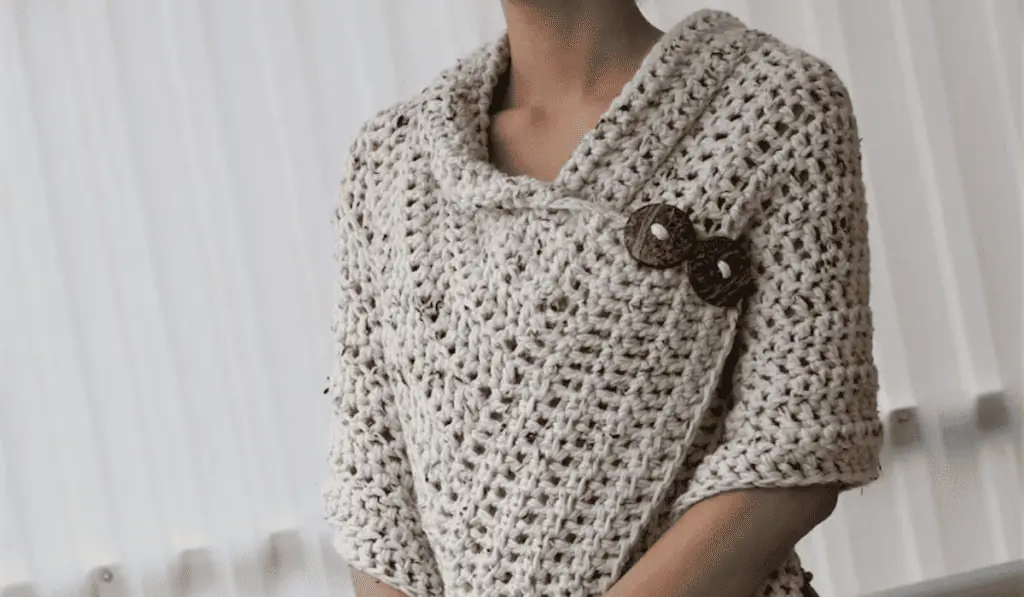 An off-white crochet poncho with buttons