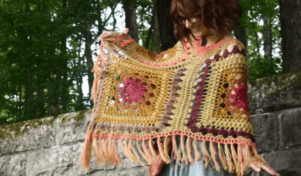 A crochet poncho with flower square designs.