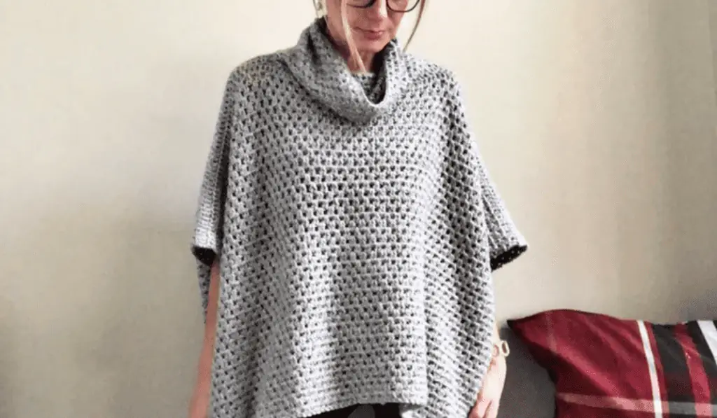 A grey crochet poncho with a square design.