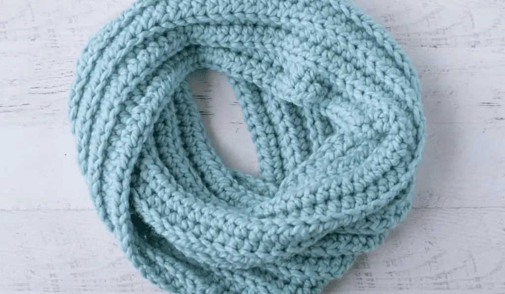 A blue ribbed scarf curled in a circle.