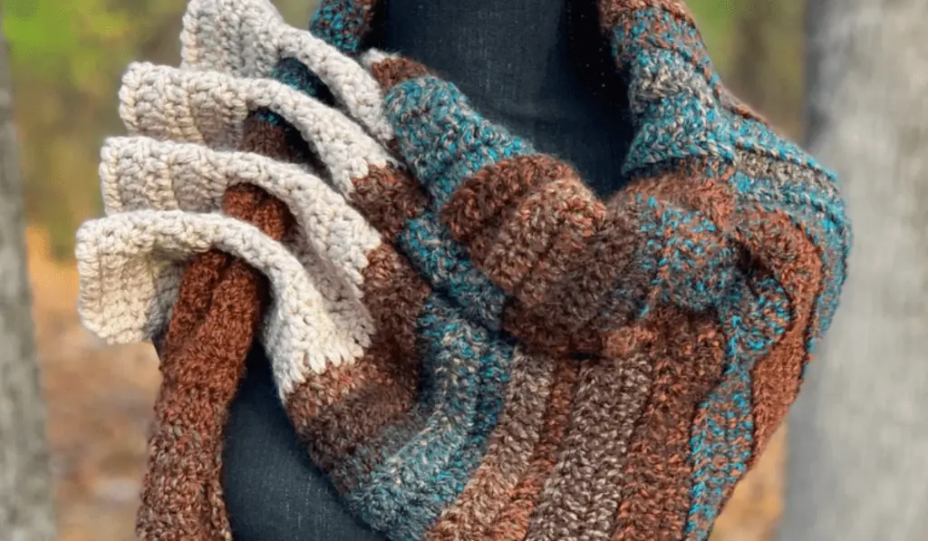 A adjustable keyhole scarf pattern with brown, dark blue, and white yarn.