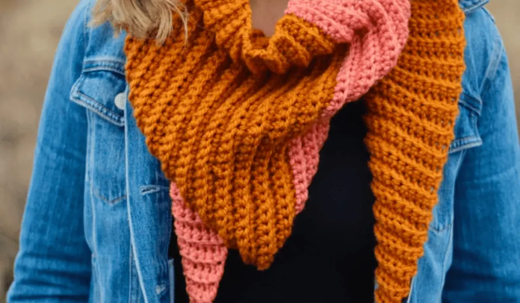 A triangle crochet scarf with have using orange yarn and half using pink yarn.