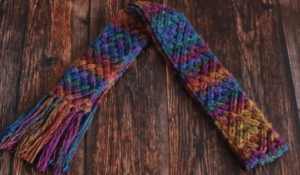 A skinny scarf with cable stitches in a varigated yarn.