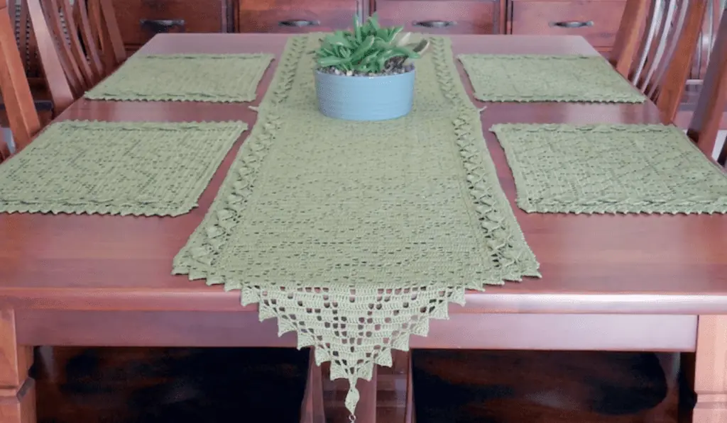 A green crochet table runner with green placemats