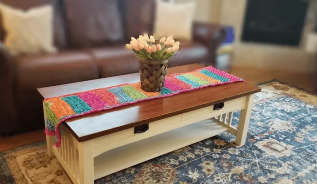 A rainbow crochet table runner on a coffee table