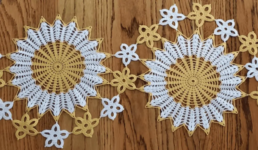 Two sunflowers with small crochet flower motifs in orange and white yarn.