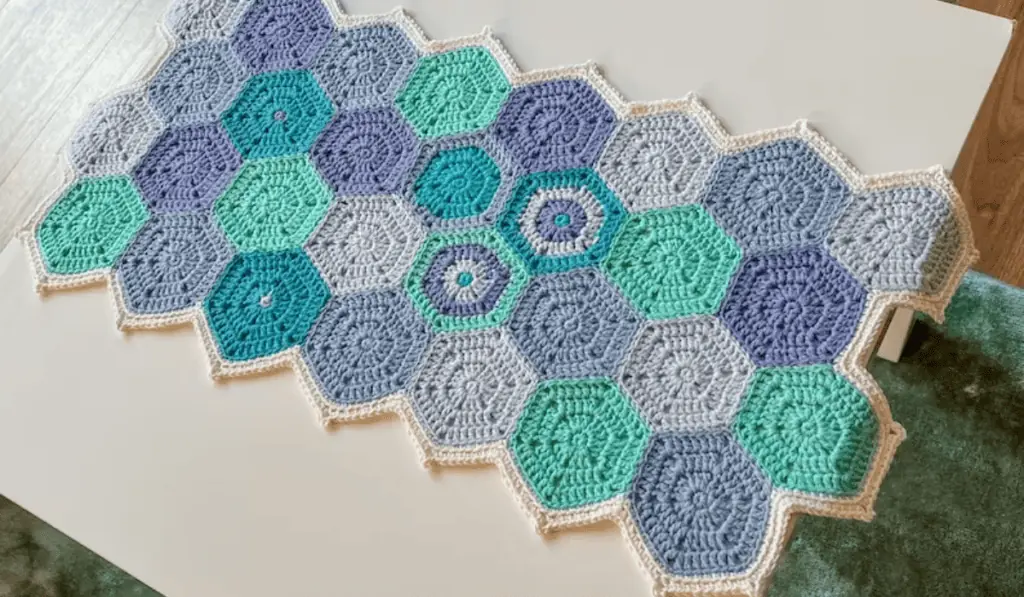 A crochet hexagon table runner with different shades of blue crochet hexagons