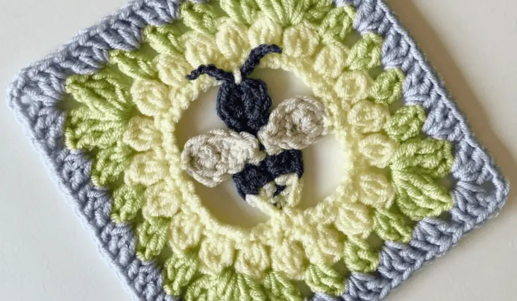 A granny square with a bee design in the middle