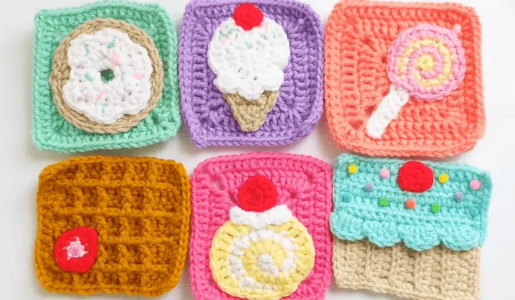 Six granny squares that look like sweet treats, one is a donut, one is an ice cream, one is a lolipop, one is a waffle, one is a round candy, and one is a cupcake.