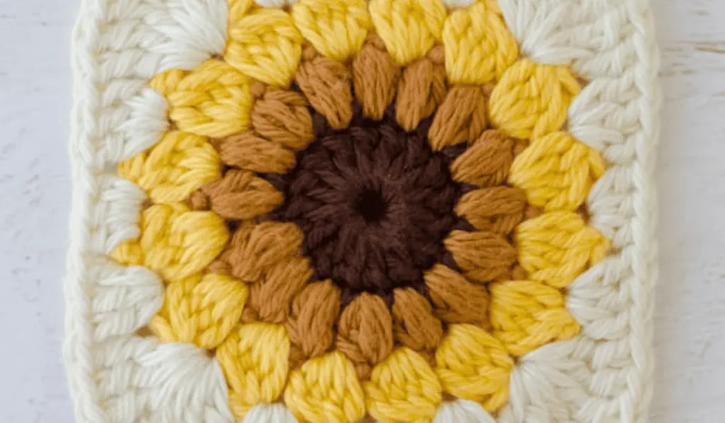 A sunflower granny square with a white border.