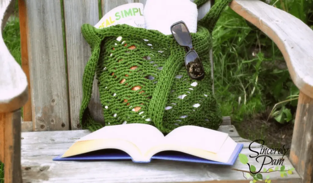 A green crochet market bag with a book in front of it.
