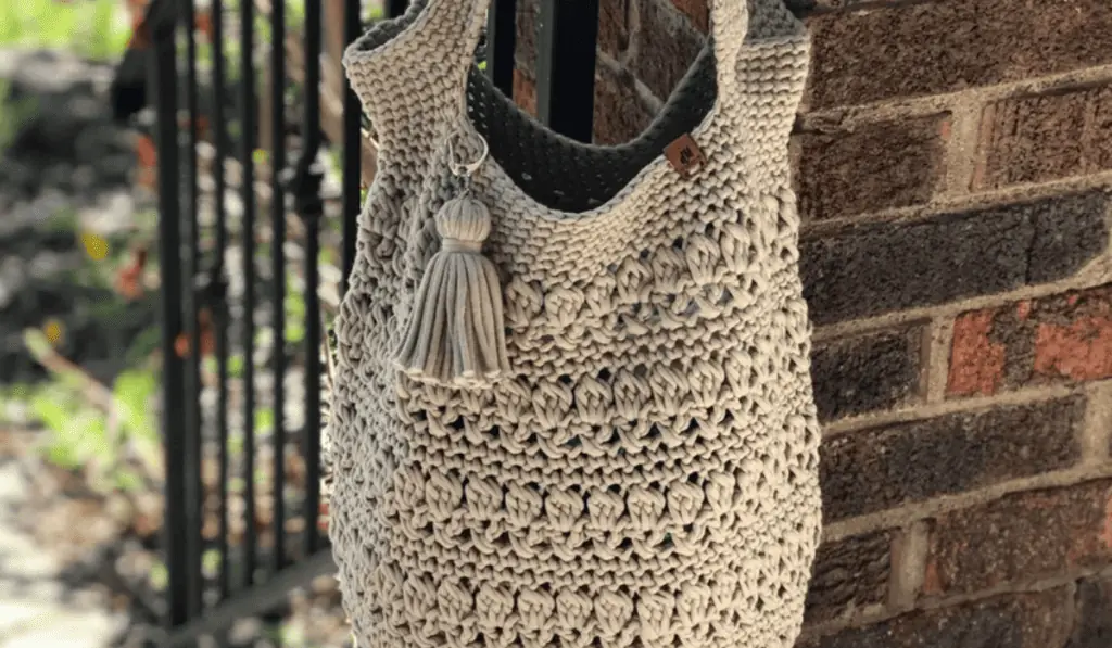 A beige crochet tote bag with a lot of textured stitches.