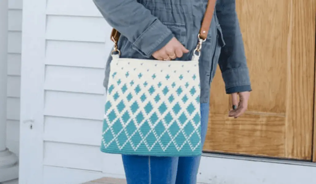 A tapestry crossbody crochet bag with a diamond design. Small diamonds are on top and each row towards the bottom the diamonds get bigger.