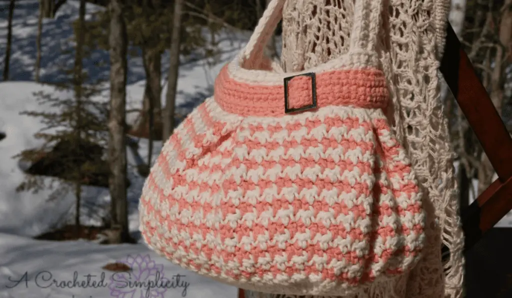 A pink and white shoulder bag with a buckle along the top.