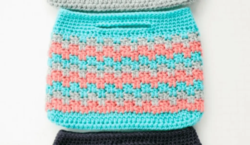 A small pouch crochet bag with lines of blue, grey, and pink yarn.