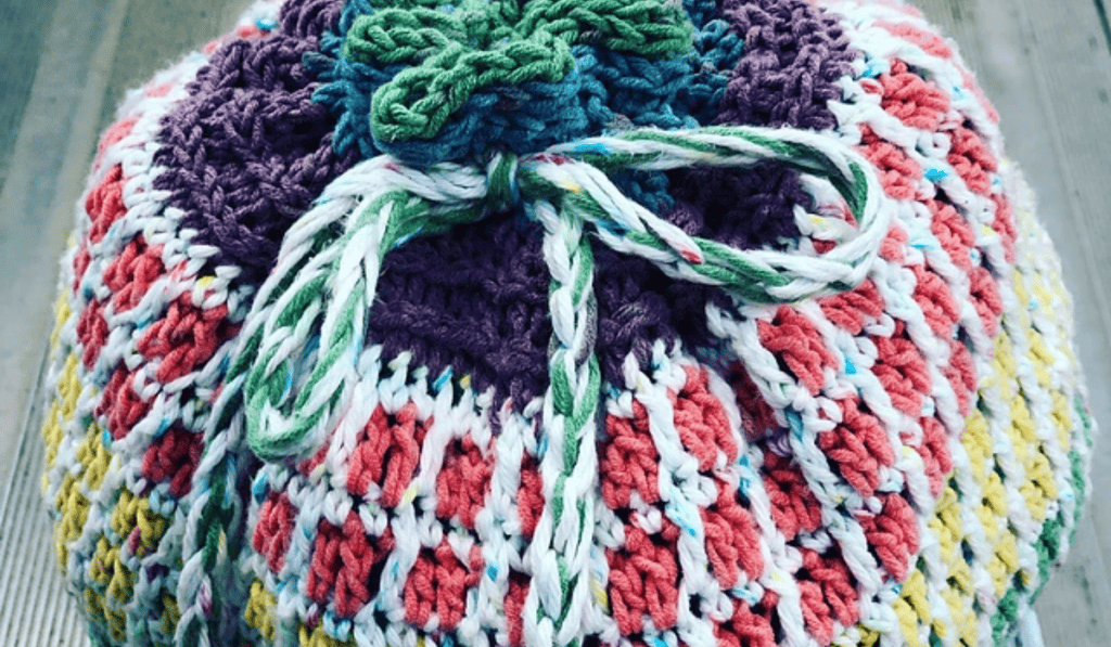 A crochet circular bag with a drawstring closure.