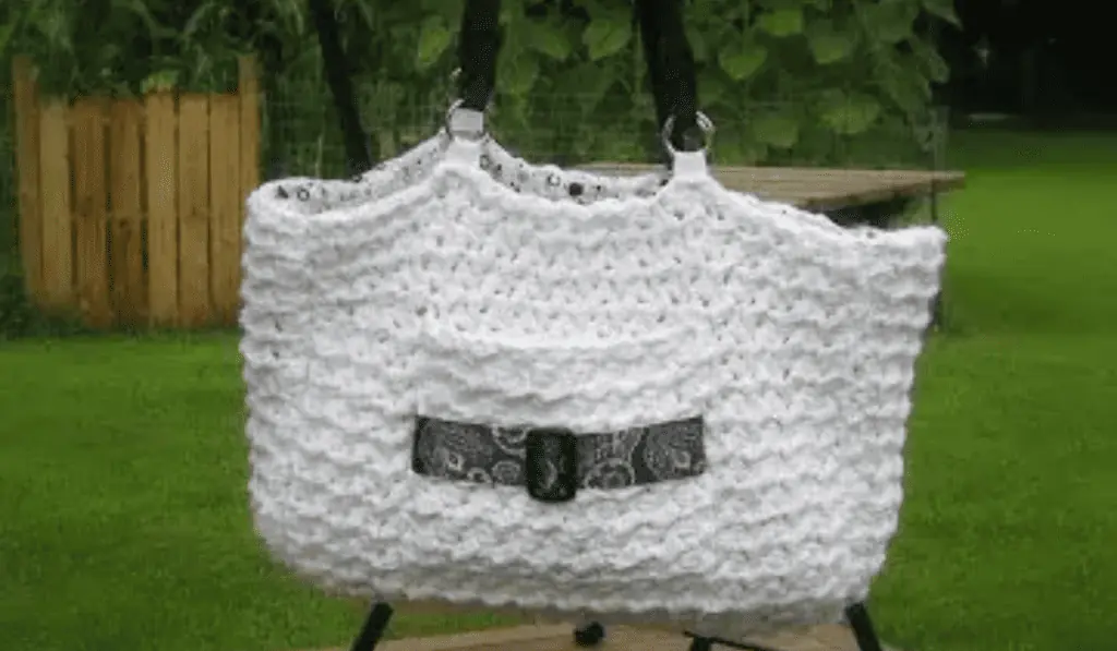 A white crochet bag with a pocket on the outside.