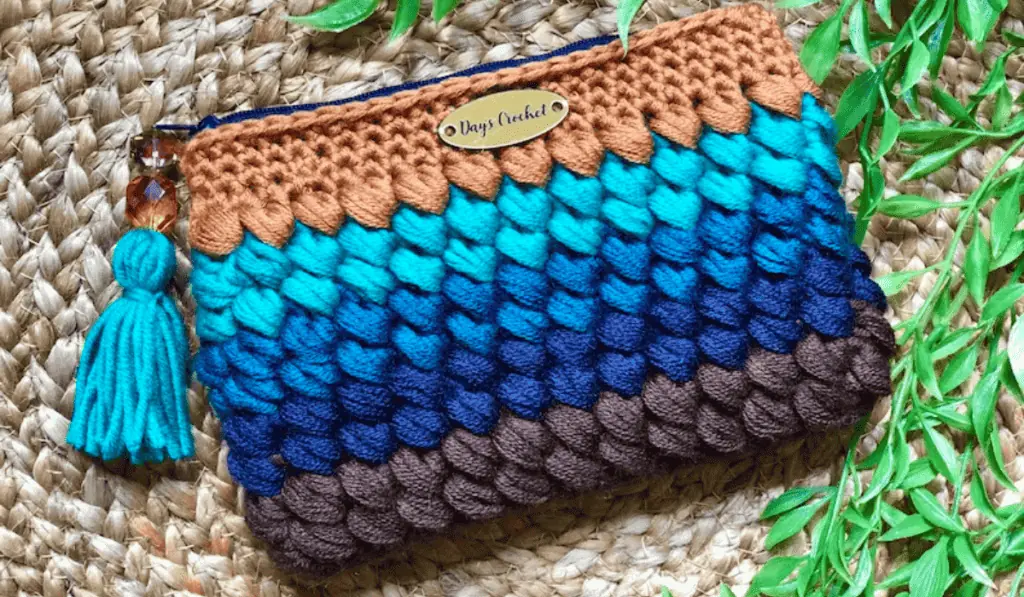 A crochet zipper pouch with a gradient of blue rows.