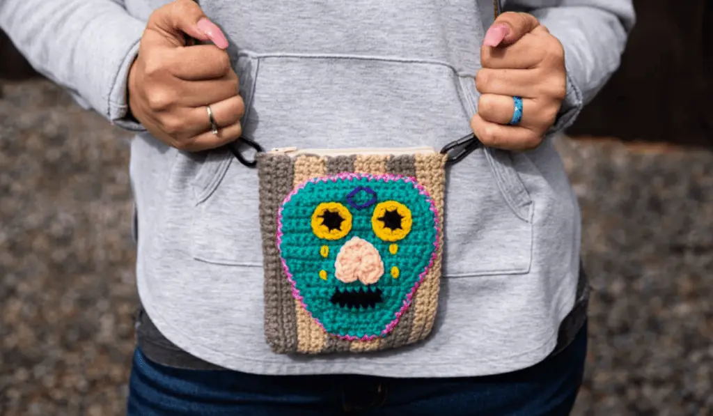 A crochet crossbody with a sugar skull on it.