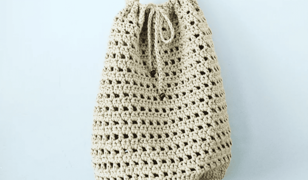 A white crochet bag with a drawstring closure.