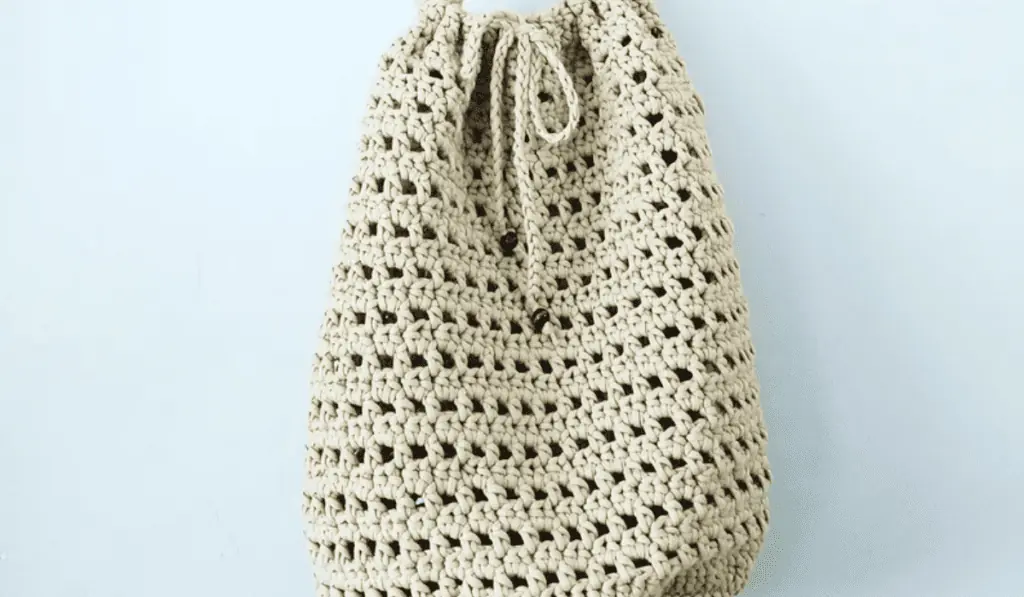 A white crochet bag with a drawstring closure.