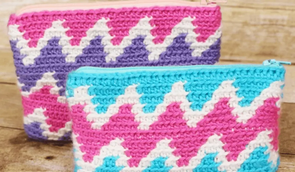 A zipper crochet pouch with blue, white, and pink yarn on one pouch and pink, white, and purple yarn on the other.