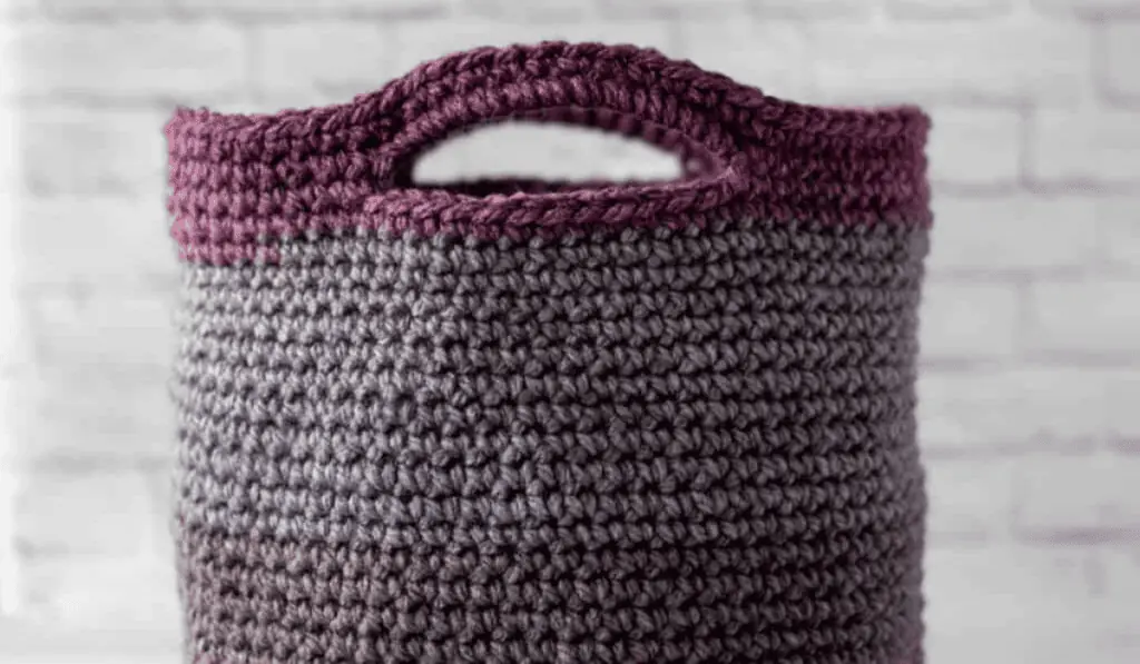 A crochet basket tote with different shades of purple color blocks.