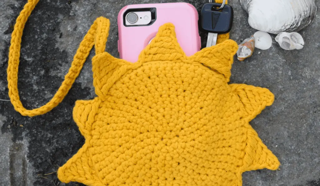 A crochet sunflower bag crossbody made out of yellow yarn.