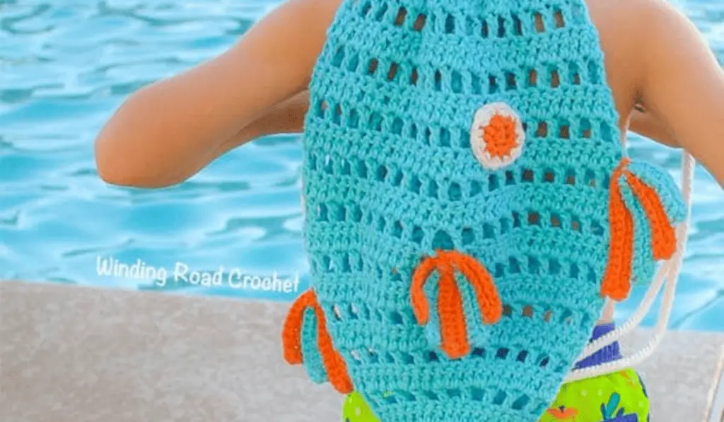 A blue crochet fish backpack with orange details.