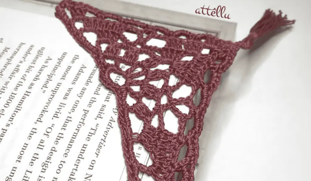 A corner crochet bookmark with maroon yarn.
