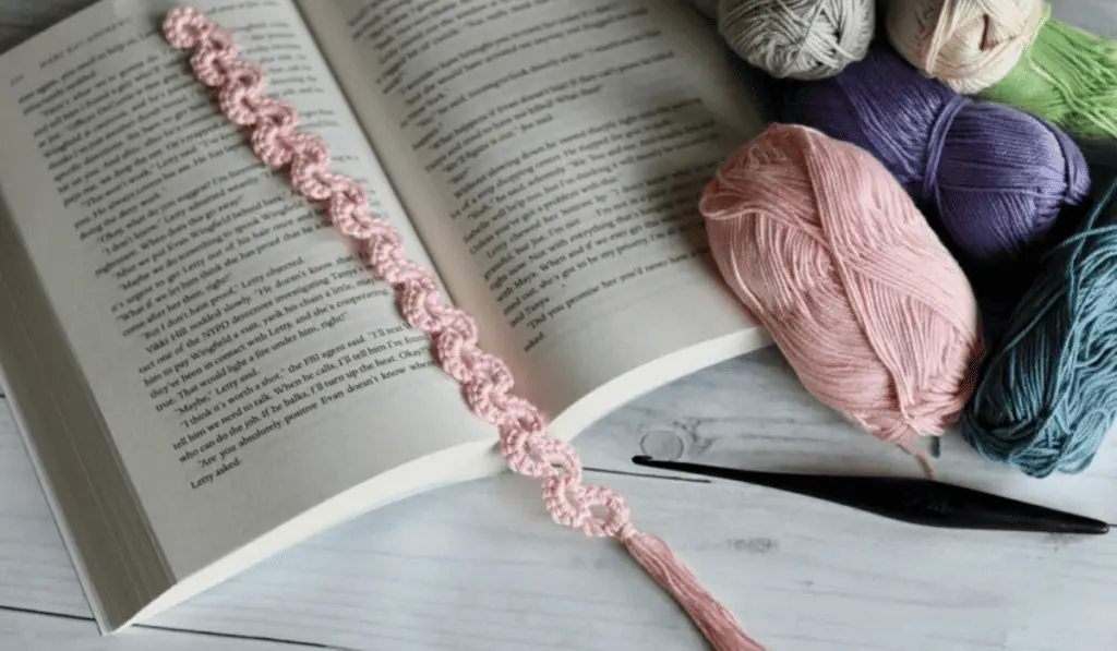A pink crochet bookmark with a curl design.
