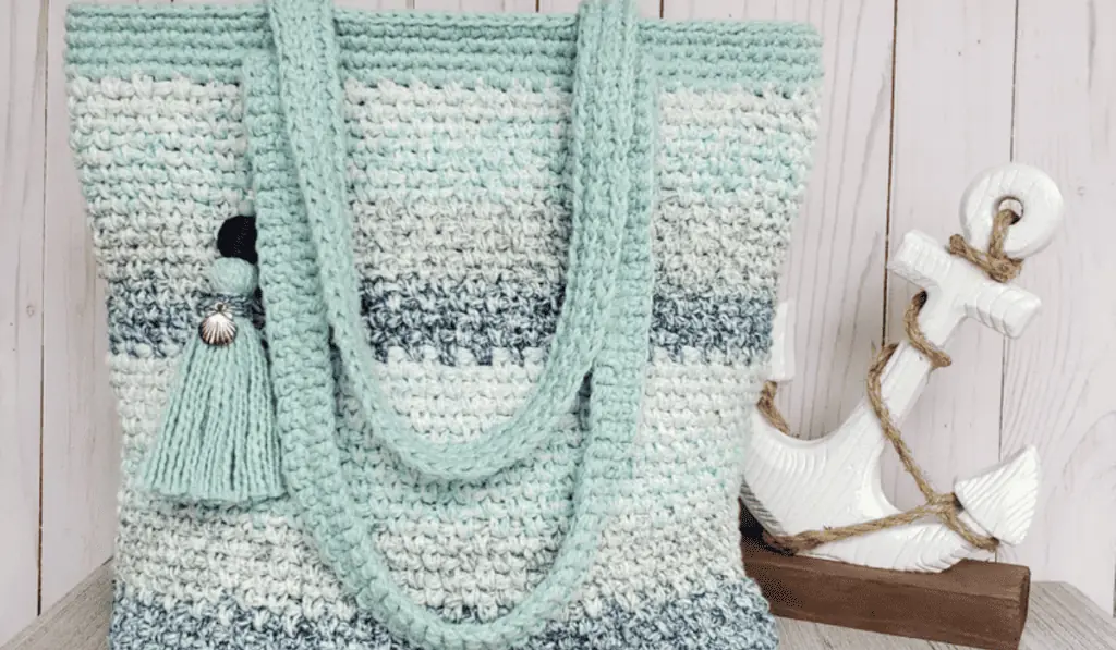 A crochet tote bag with different shade of blue stripes.
