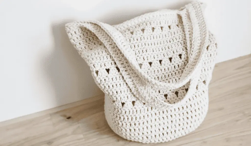 A white crochet tote bag with small triangle cut outs.