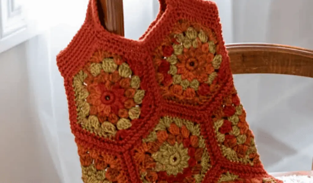 Hexagon-shaped granny squares featuring green and orange yarn assembled into a small tote bag.