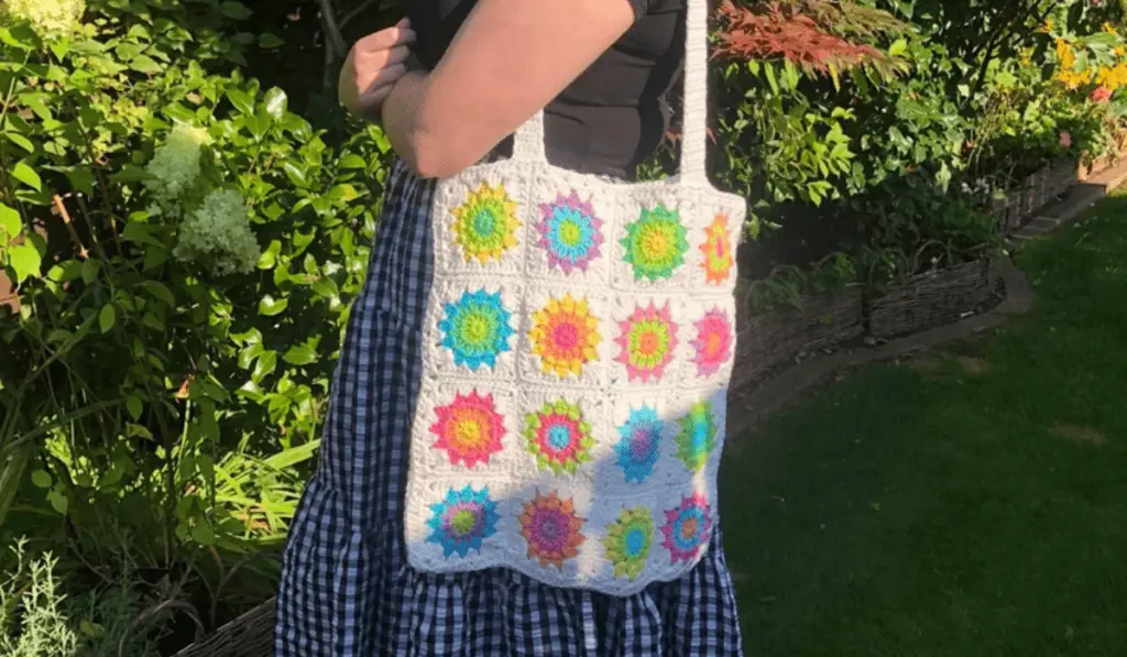 A crochet tote bag with a white background and neon sunburst granny squares.