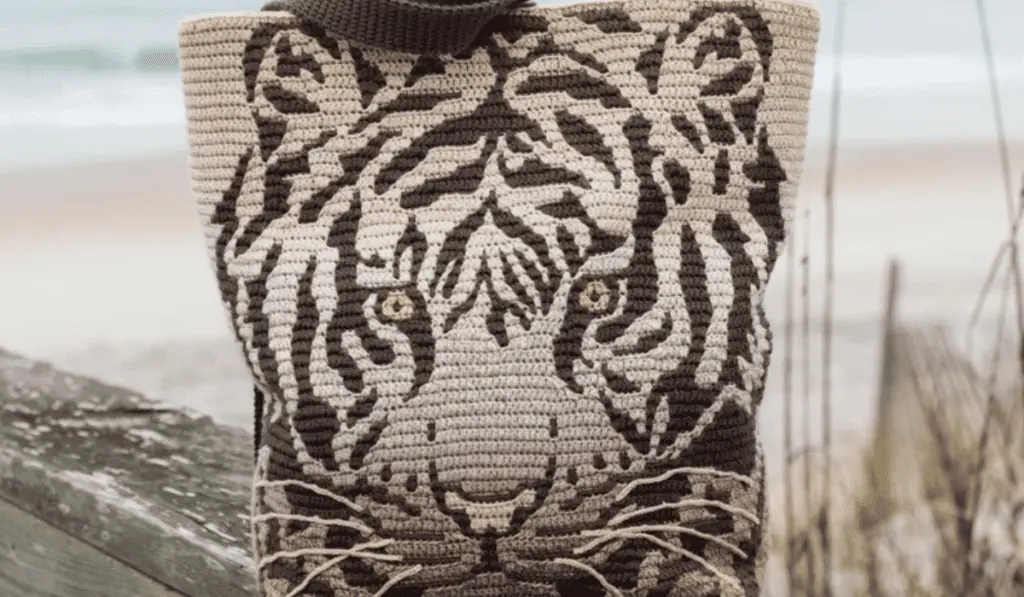 A tiger-design crochet tote bag with a light brown background and dark brown stripes.