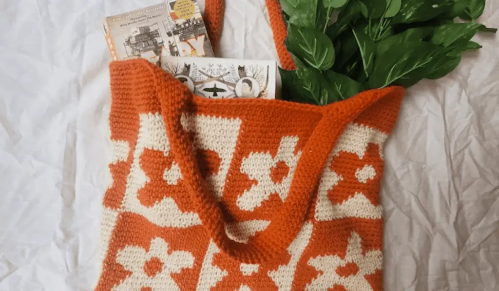 A 70s style flower tote back with inverted yarn and flower colors in every other block. This bag is in white and orange yarn.