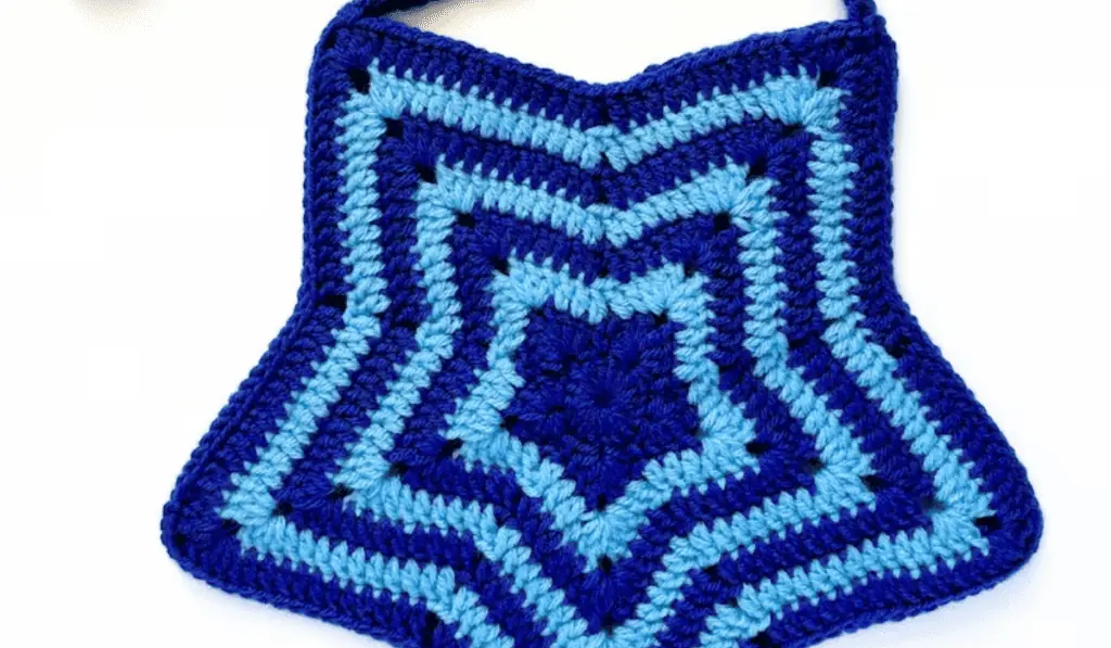 A crochet tote bag pattern that is shaped like a star. This pattern uses dark blue and light blue yarn and interchanges it at every row.