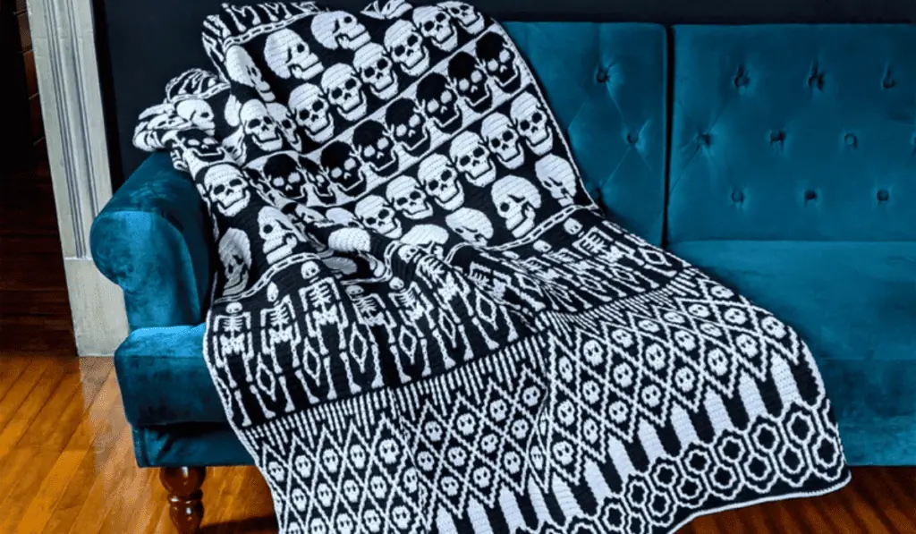 A mosaic crochet blanket pattern that's made with black and white yarn and variety of different shaped skulls.