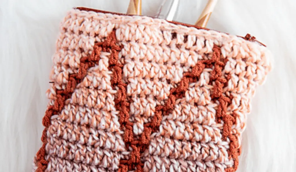 A mosaic crochet zipper pouch with pink background and diamond details.