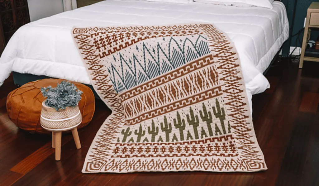 A mosaic crochet blanket pattern with cacti and small mountain ranges with a variety of geometric shapes.
