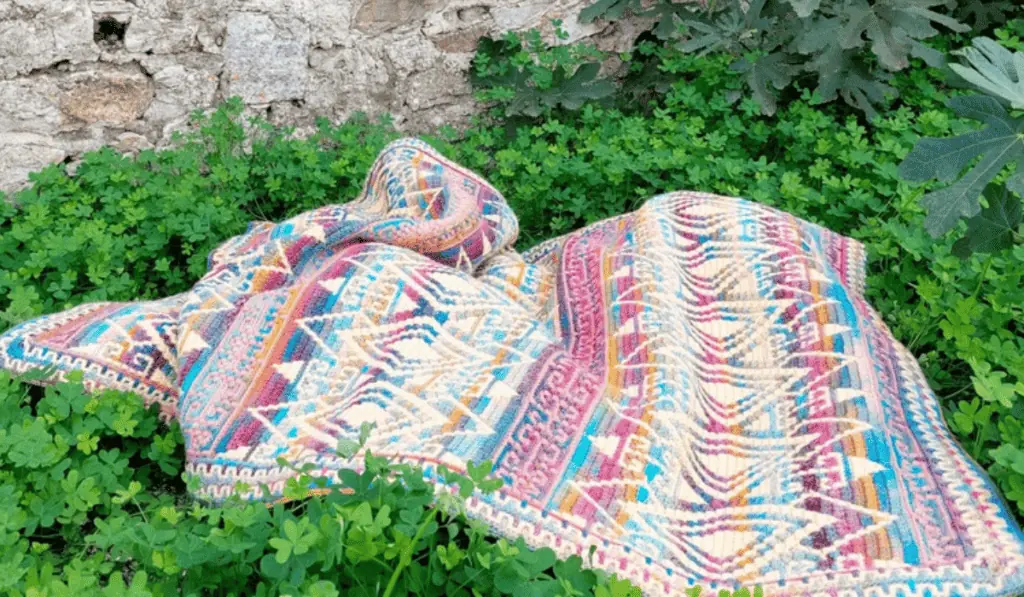 A mosaic crochet blanket pattern with mutlicolored yarn and a geometric design.