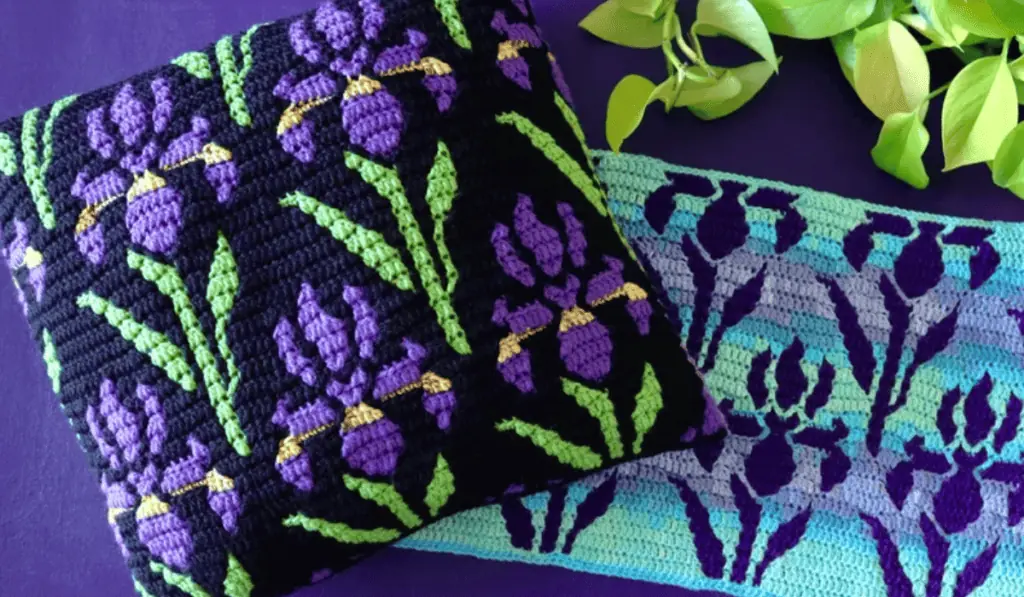 A mosaic crochet pillow pattern with purple iris flowers on it.
