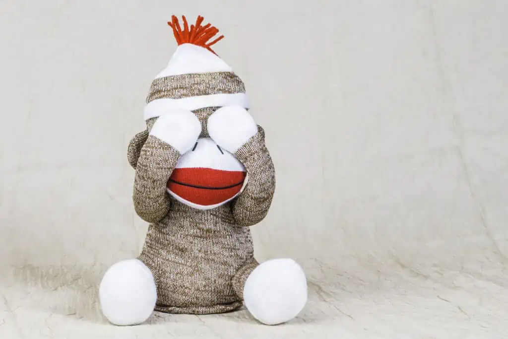 Sock monkey covering eyes made from brown and white mens socks