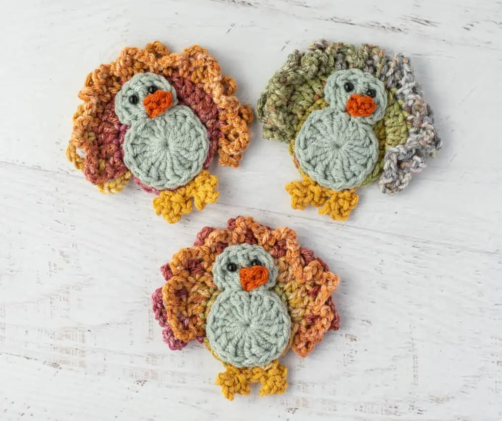 3 Crochet turkeys with blue gray bodies and yellow feet