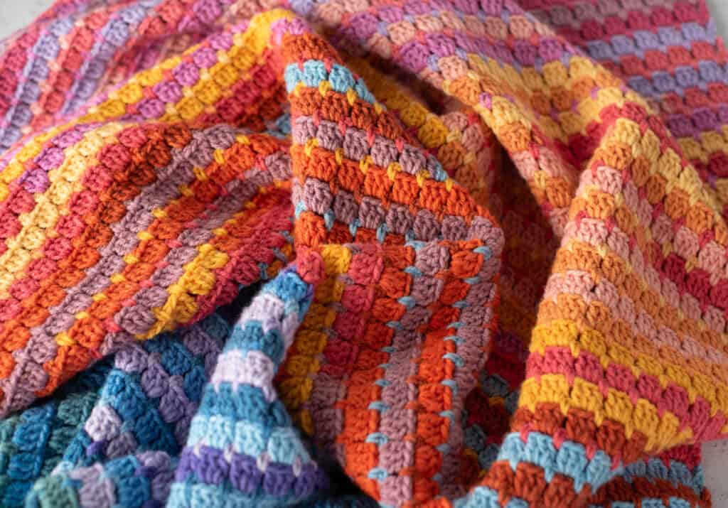 Multicolor yarn crochet afghan in orange, blue, purple assorted shades