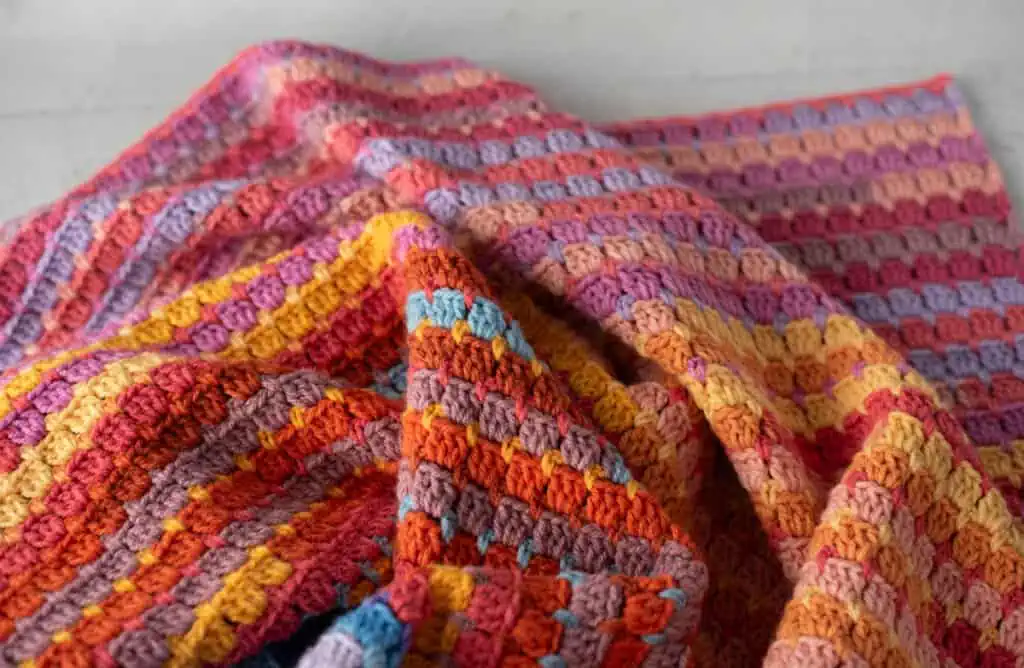Multicolor yarn crochet afghan in orange and purple hues