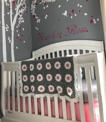 Crochet daisy baby afghan laying on crib.