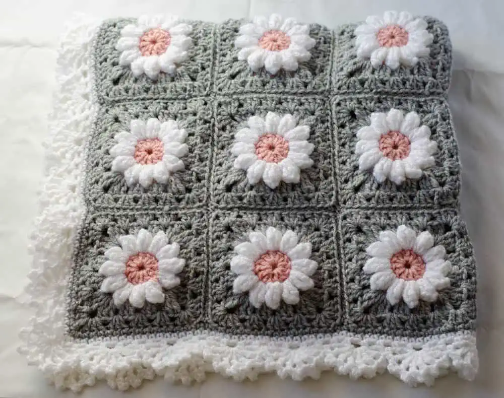 Folded crochet daisy granny square afghan in gray, pink and white